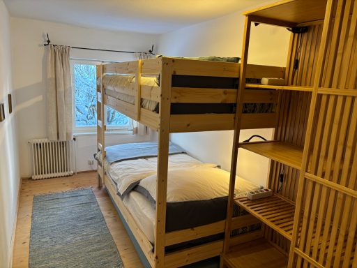 "Familienzimmer - Kinder" Helles Zimmer mit Etagenbett, zwei Betten und Holzregal.