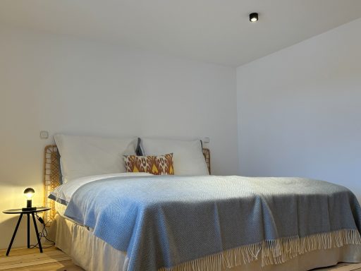 "Stubenschlafzimmer" Helles Schlafzimmer mit einem großen Bett, kuscheliger Decke und minimalistischer Dekoration.