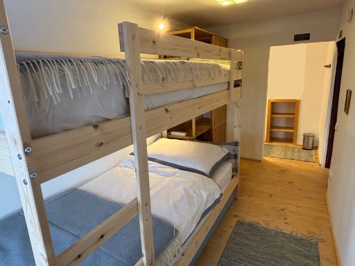 "Familienzimmer - Kinder" Gemütliche Schlafrakete mit Etagenbetten und Holzregalen in einem hellen Raum.