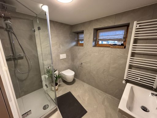 Großes Badezimmer Modernes Badezimmer mit Dusche, Toilette, Waschbecken und Fenster.